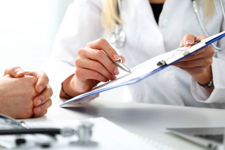 Female doctor hand hold silver pen filling patient history list Female doctor hand hold silver pen filling patient history list